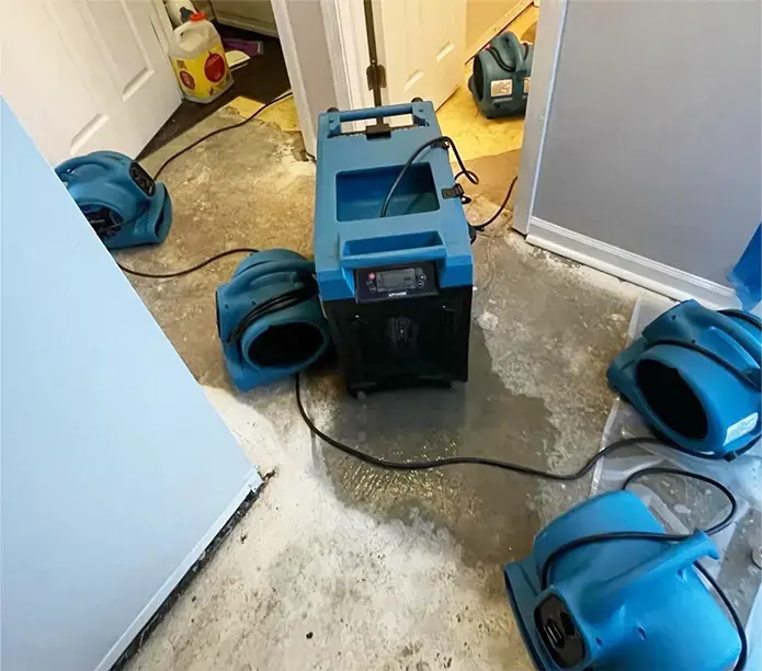 Air movers and a dehumidifier drying a wet floor in a Rochester home