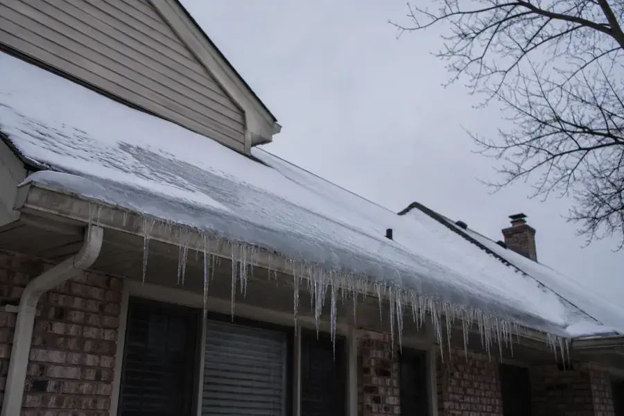 Ice dam and icicles along the snow-loaded eaves of a Rochester home